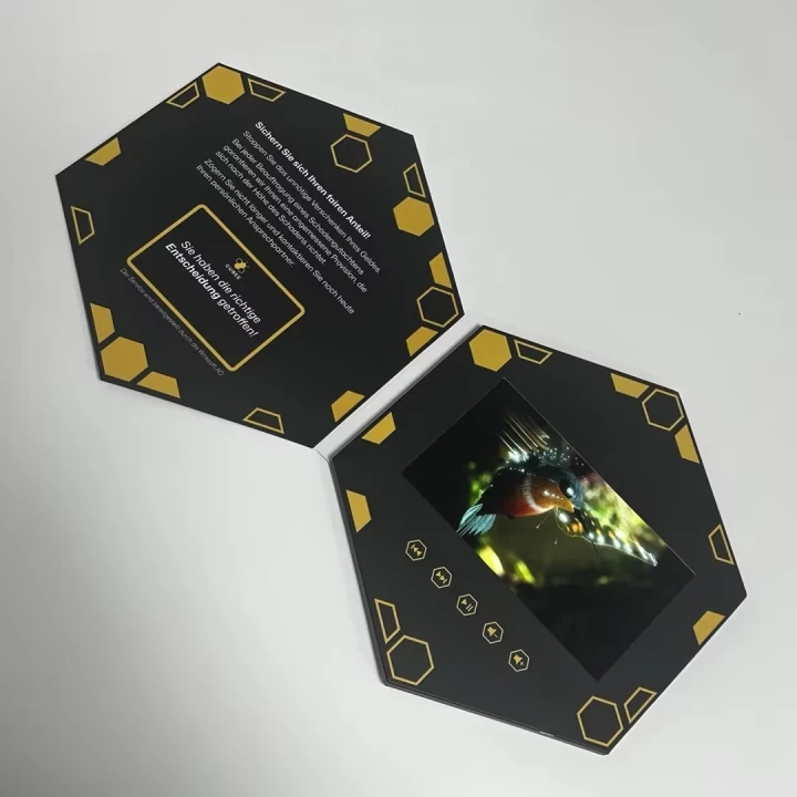 Hexagon-shaped custom video brochure with 7-inch IPS screen, modern gold graphic design, and interactive playback buttons